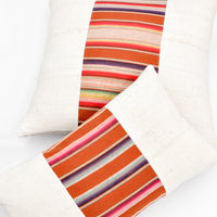1: Square and rectangular throw pillows with plain ivory left and right sides, and striped center panel in earth tones.