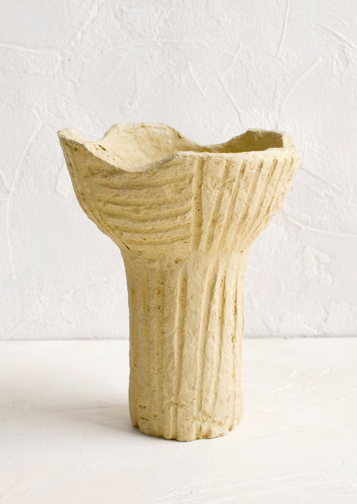 A footed paper mache pedestal bowl with line texture.