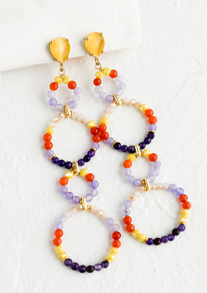 A pair of beaded earrings with four beaded circle shapes and faceted teardrop post.