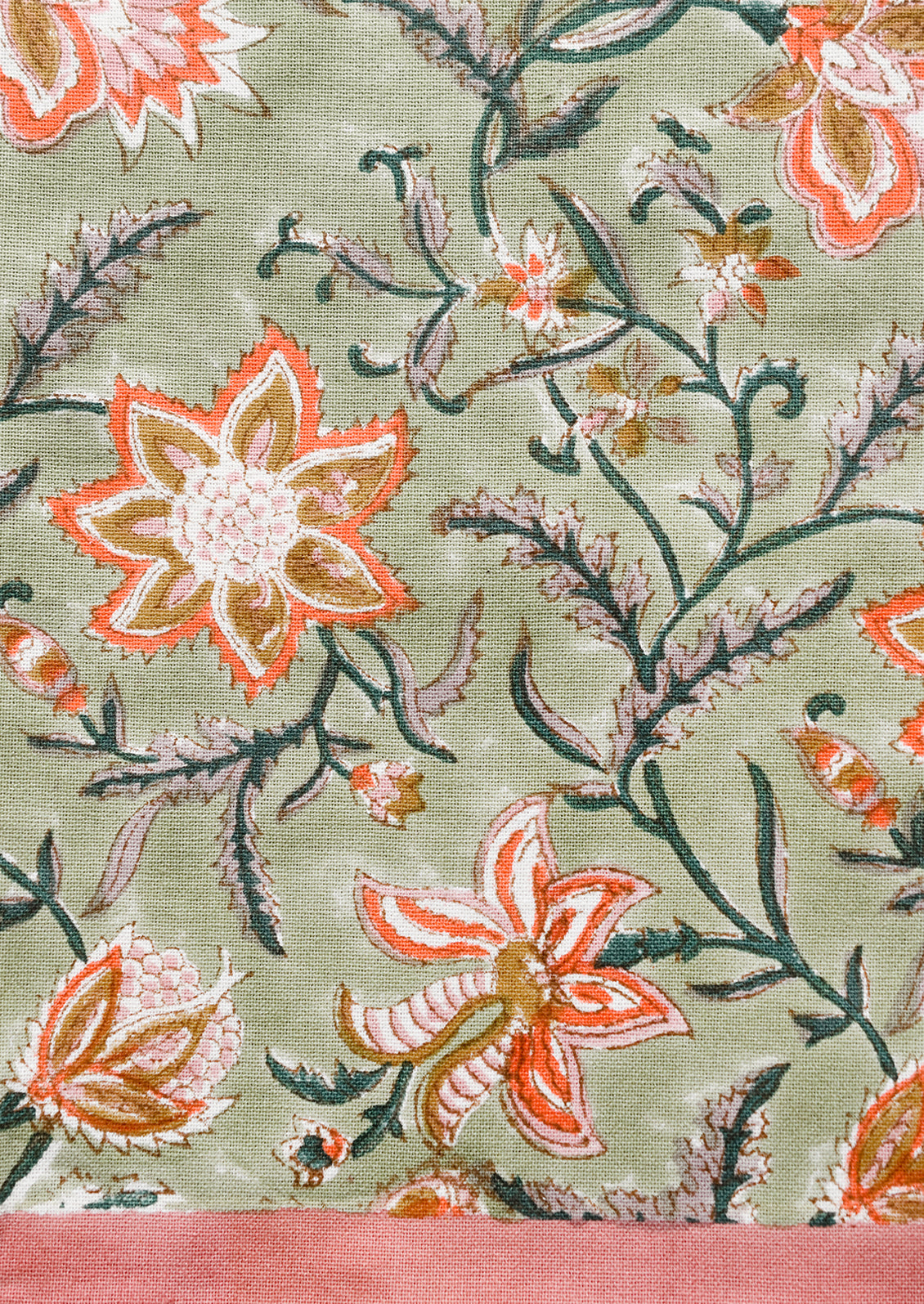 A tea towel with sage green background and orange and pink floral print.
