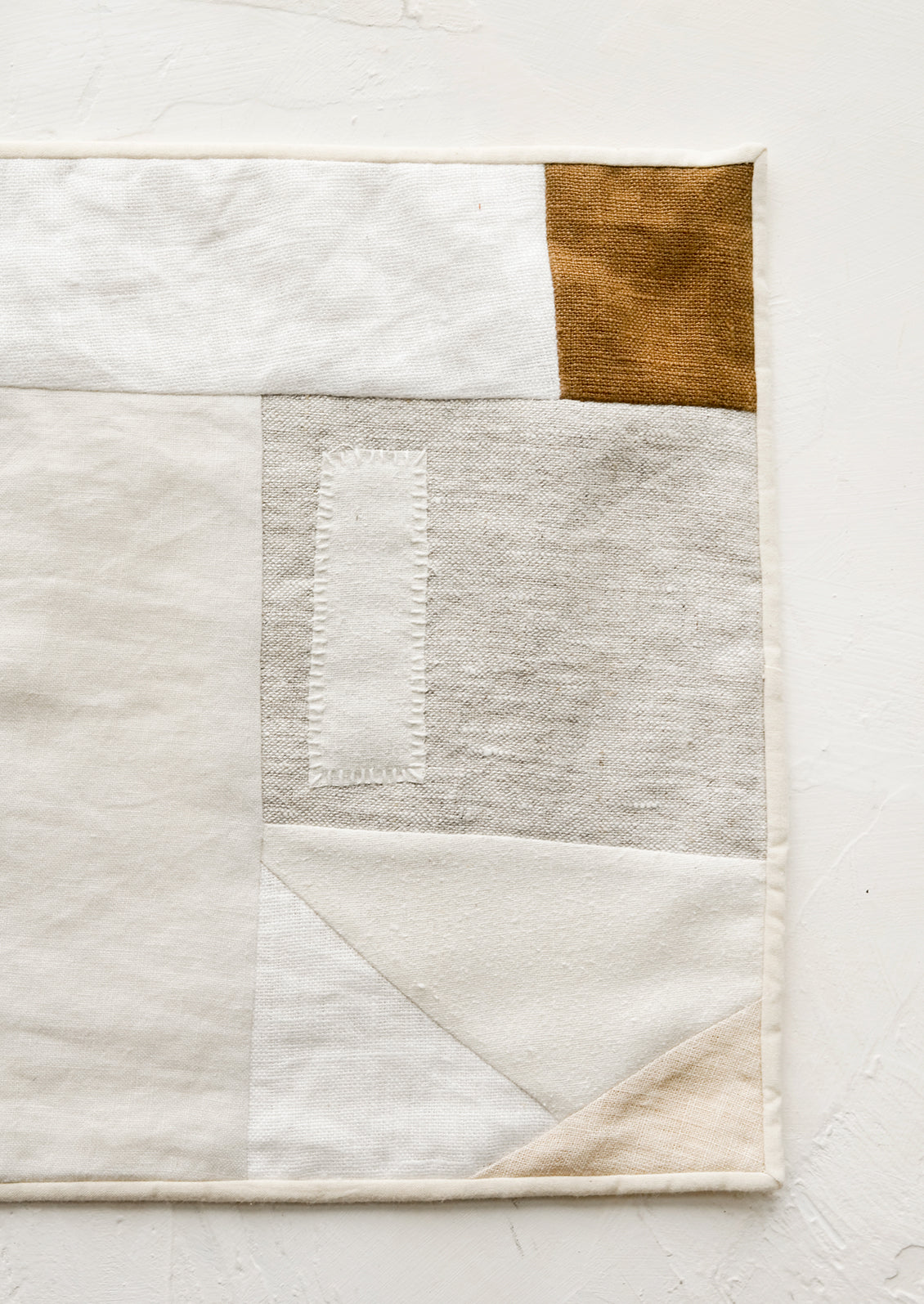A rectangular placemat with patchwork design in natural shades.