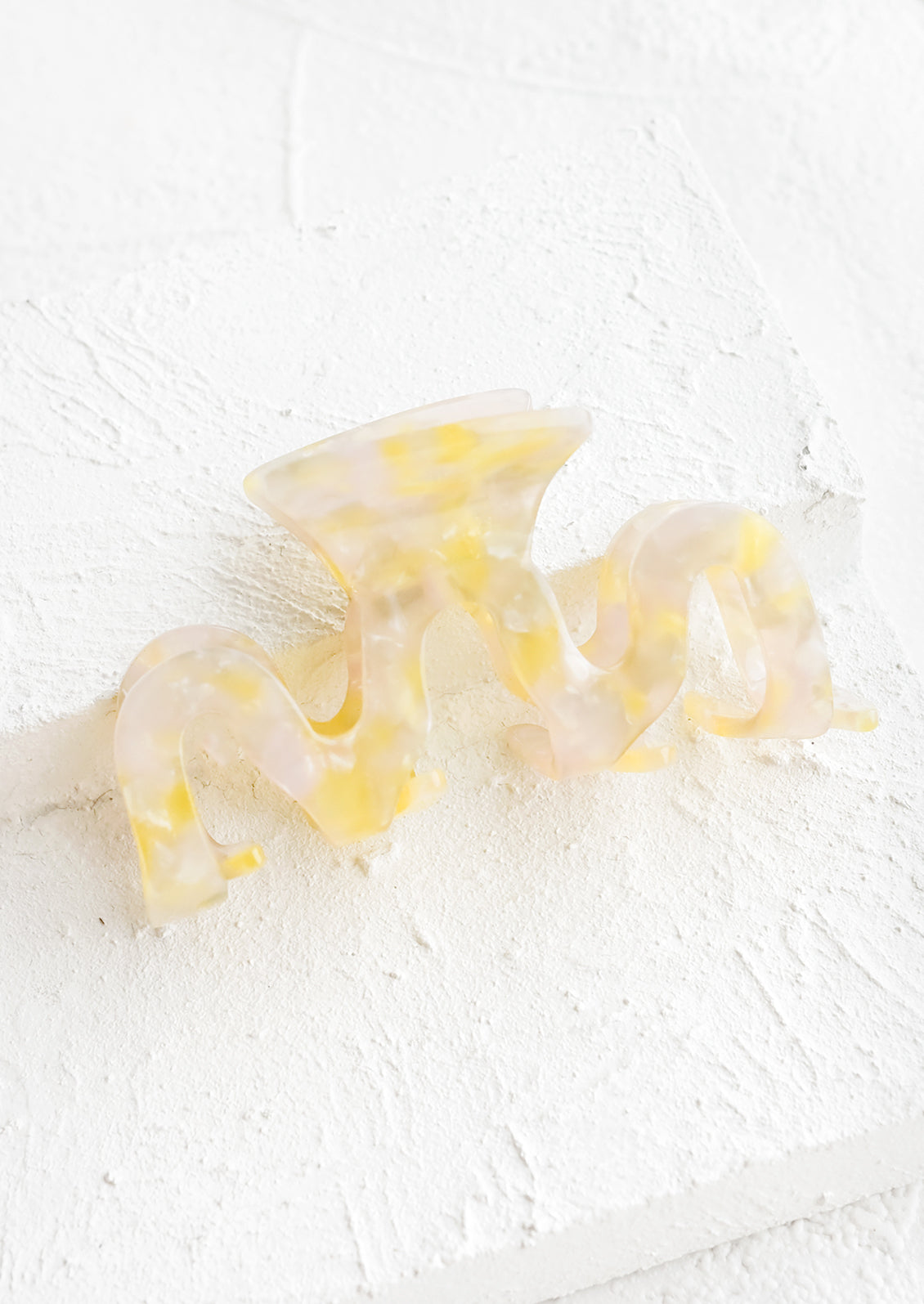 An acetate hair clip in squiggle shape in yellow marble.