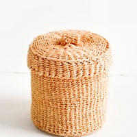 1: Small, round woven basket with matching lid made from peach-colored sisal
