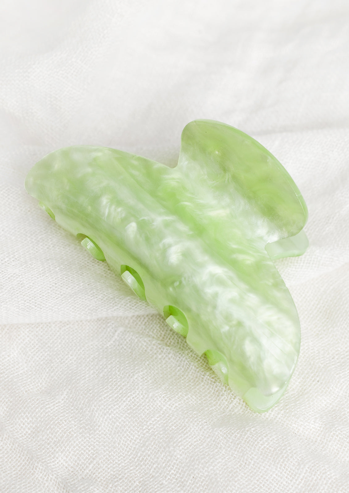 A plastic hair claw in pearlized lime.
