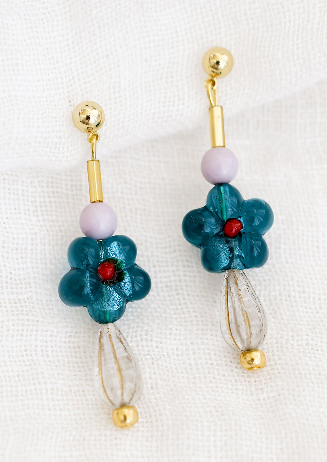 A pair of multi beaded drop earrings with teal glass flower bead at center.