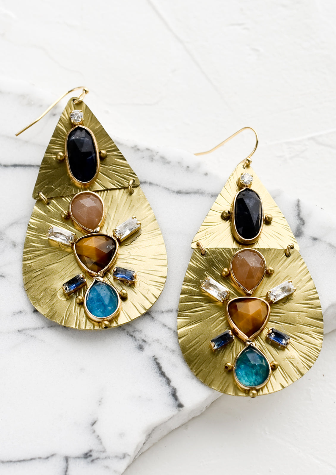 A pair of teardrop shaped gold metal earrings with crystal and gemstone embellishment.