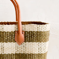 3: A raffia tote with natural leather handle and white stitching.