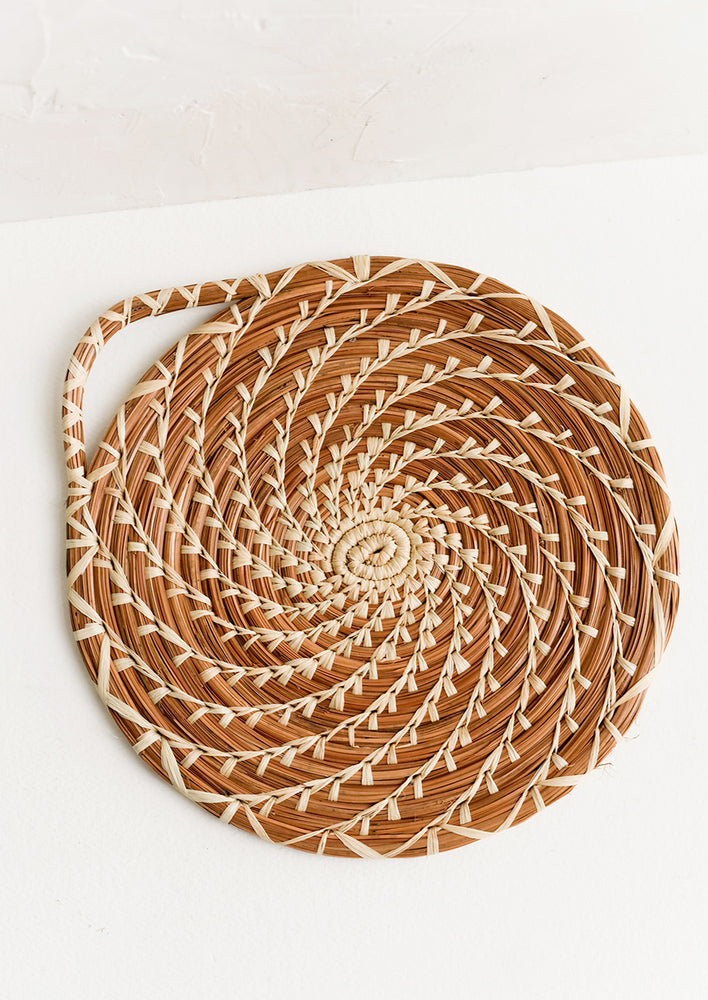 1: A round trivet with swirling design made from woven pine needles.