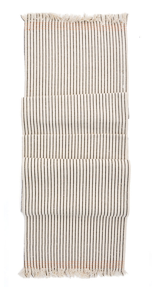 Jute table runner in natural with black pinstripes. Frayed ends with orange stitching.