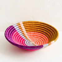 2: A round colorful woven sweetgrass basket with multicolor sunset design.