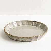 Natural / Oval: A small, oval shaped shallow dish with pleated edge in glossy natural clayglaze.
