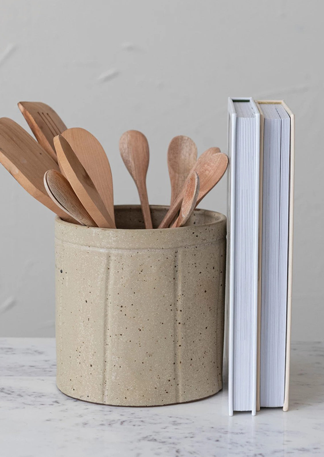 A round utensil crock in speckled tan ceramic with vertical line detail.