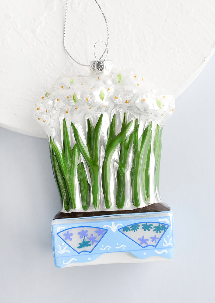 A decorative glass ornament in shape of paperwhite flowers in a planter.