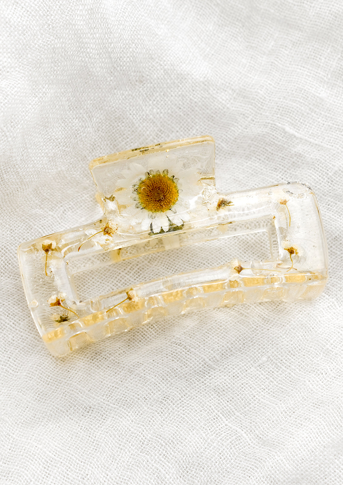 A clear resin hair clip with suspended white daisies.