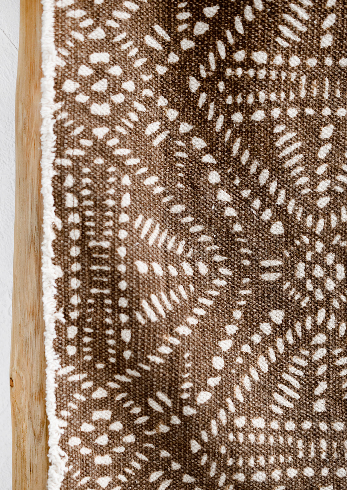 A brown canvas table runner with white resist pattern.