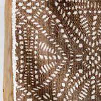 2: A brown canvas table runner with white resist pattern.