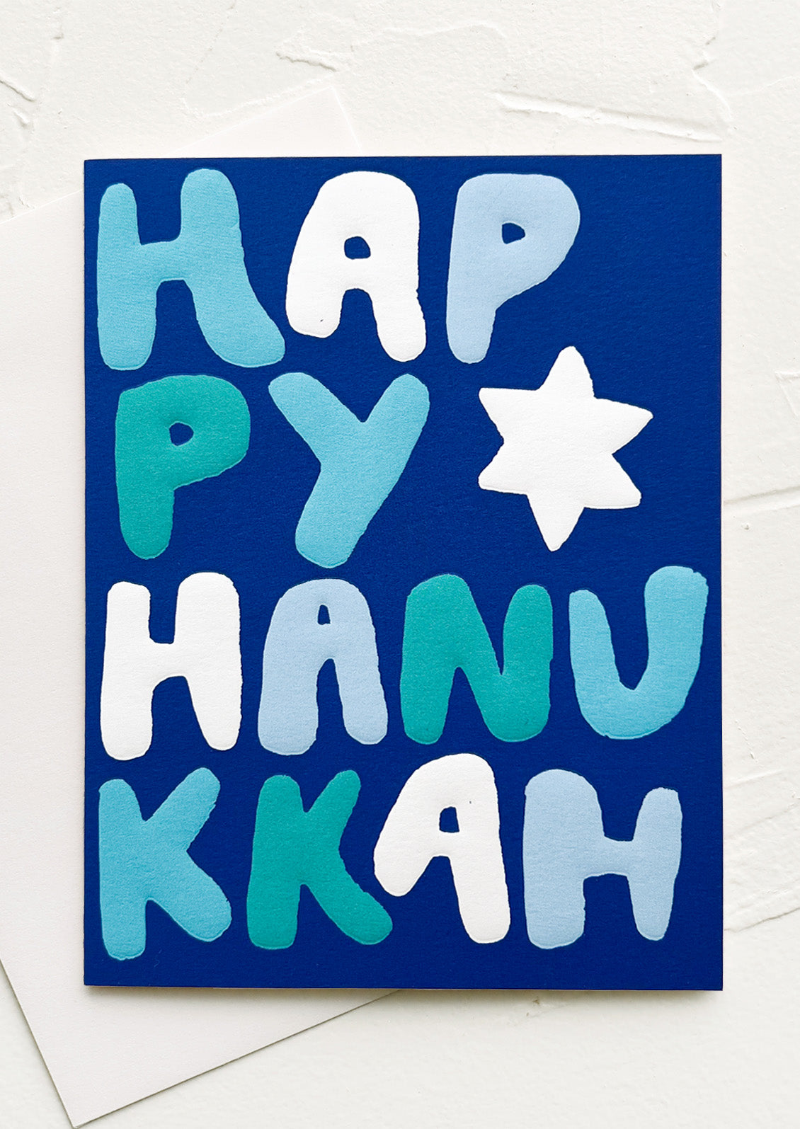 A blue card with "Happy Hanukkah" written in blue, white, and turquoise puffy letters