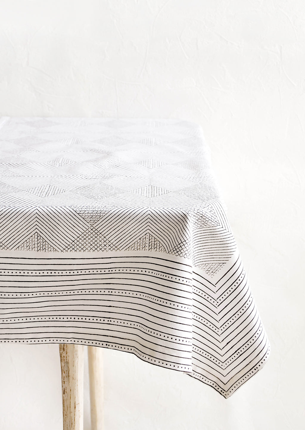 2: Black and white cotton tablecloth with geometric line and diamond print, displayed on a table