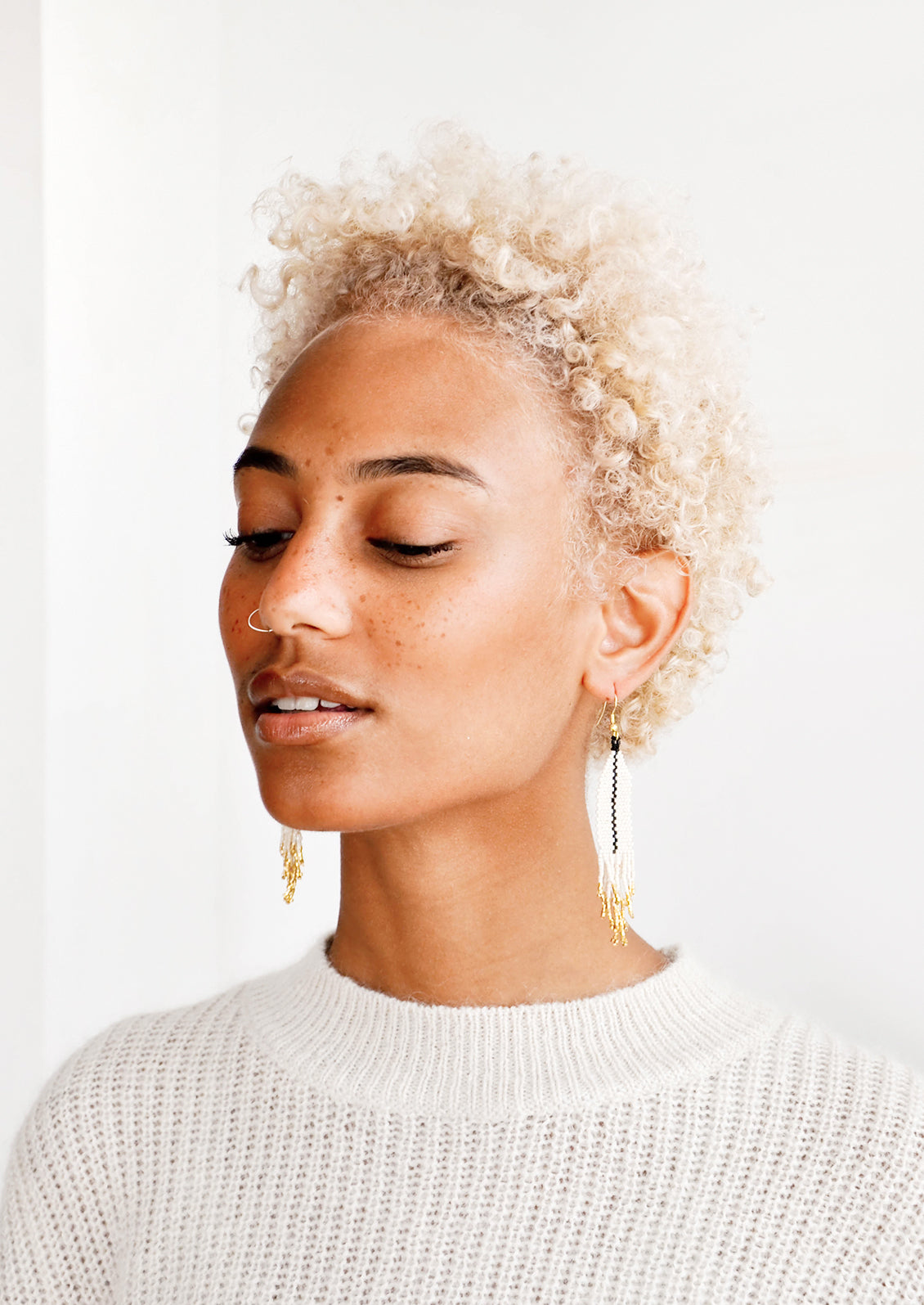 Model shot featuring woman wearing earrings and white top.