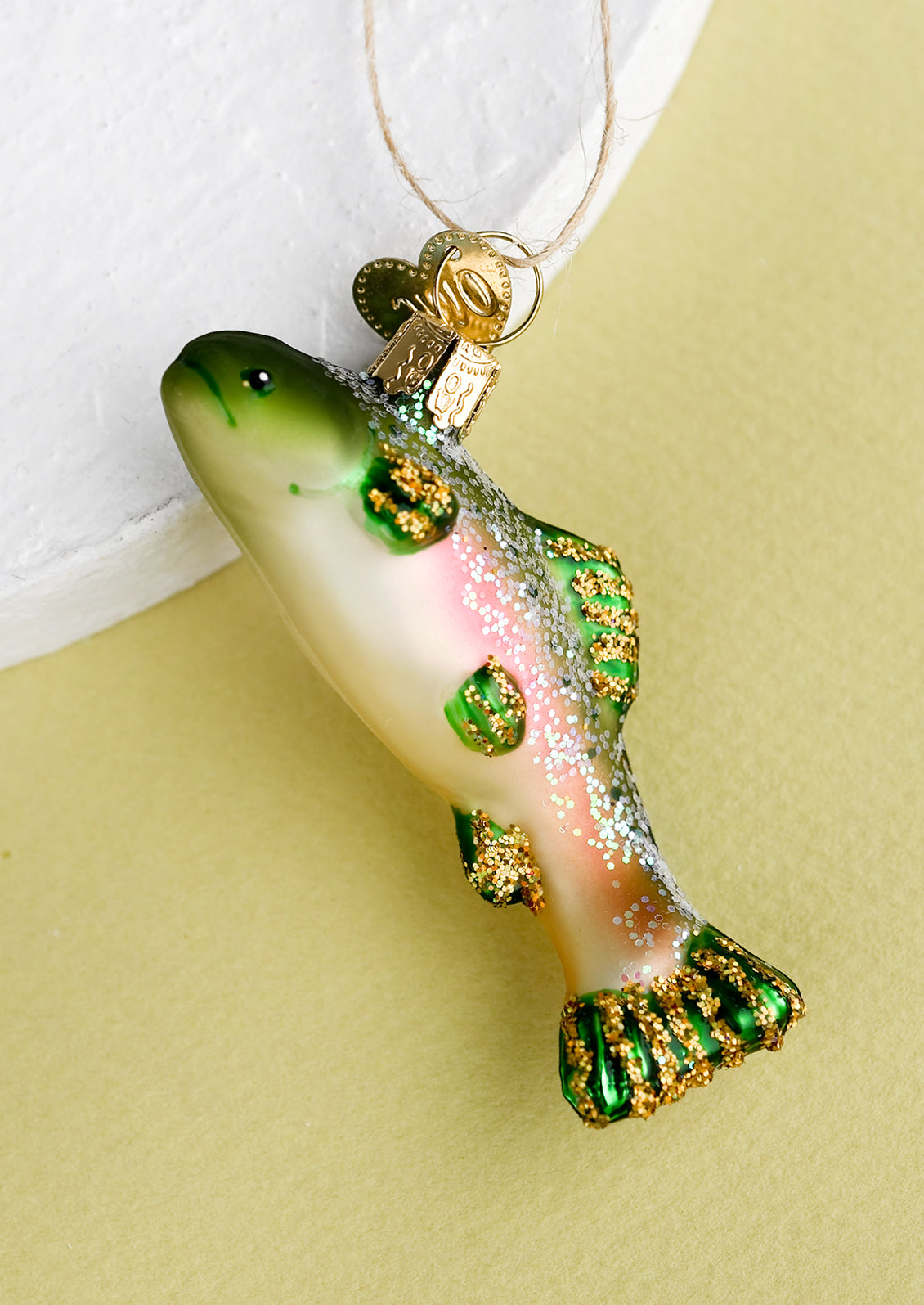A holiday ornament of a green and pink fish.