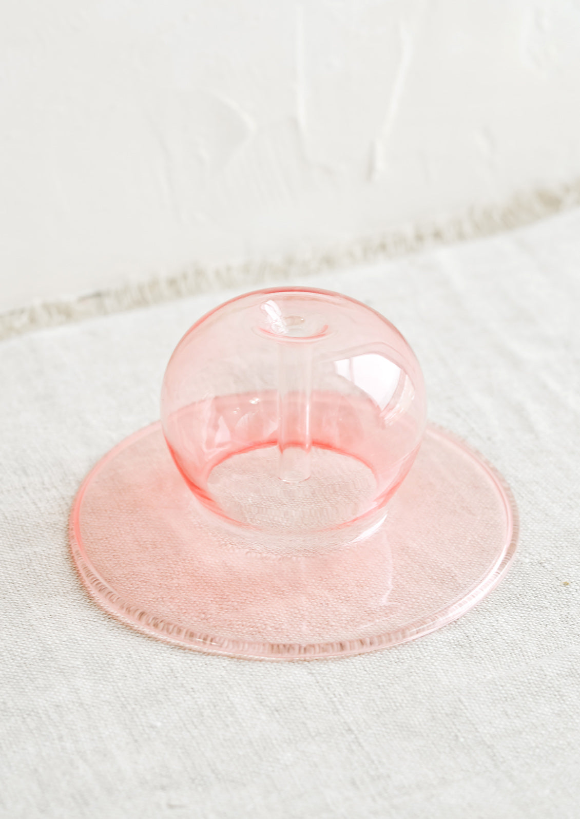 A pink bubble shaped glass form designed to hold stick incense.