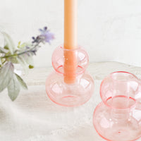 Blush Pink: Bubble shaped glass taper candle holders in pink, on a table.