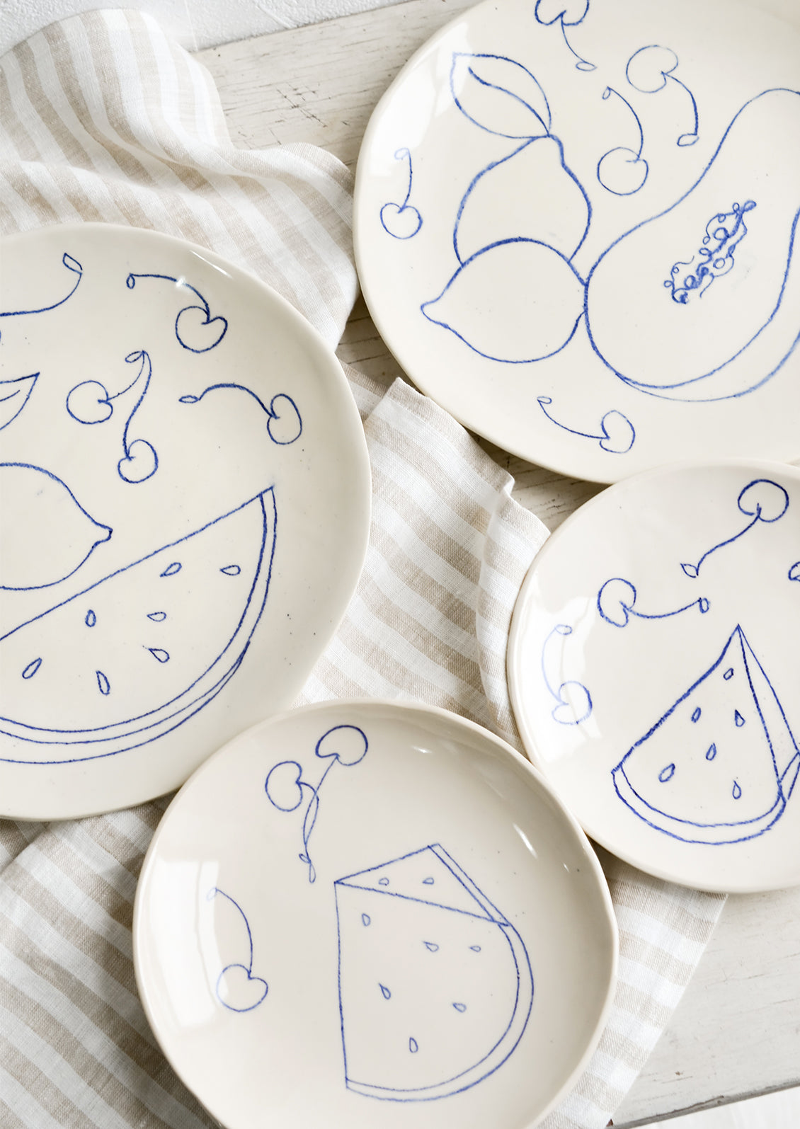 Ceramic side & dinner plates with still life fruit drawings in blue.