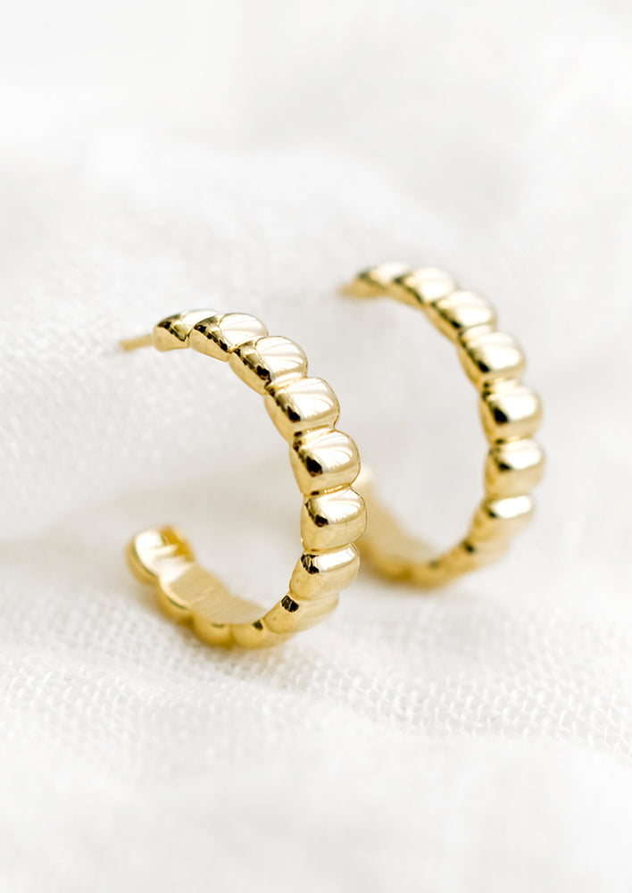 1: A pair of ribbed gold hoop earrings.
