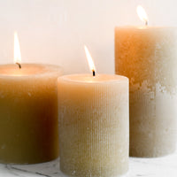 2: Three tan colored pillar candles in assorted sizes.
