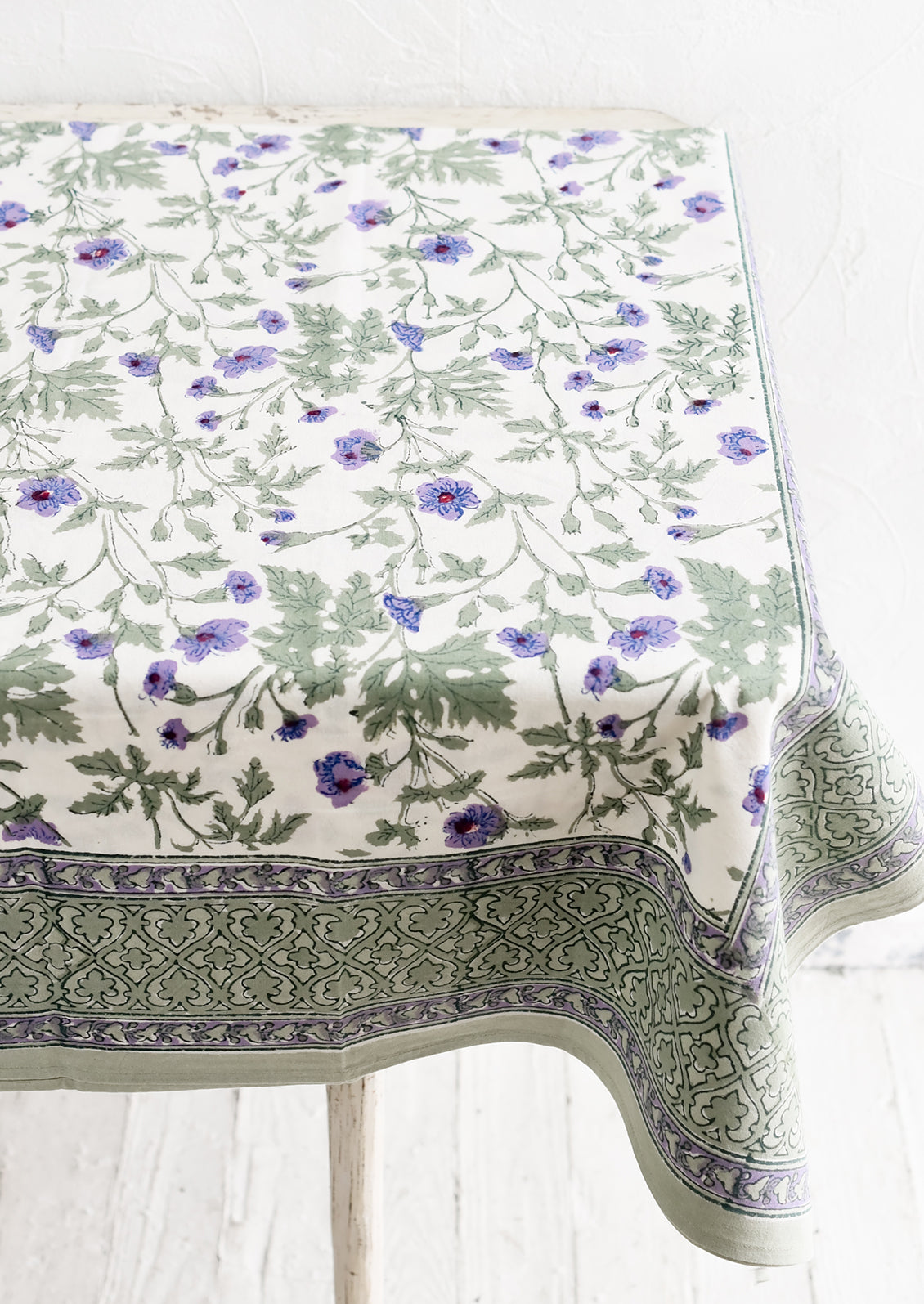A block printed floral tablecloth in purple and green floral.