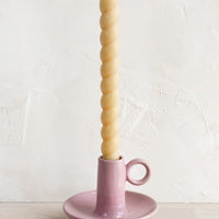 5: A pink taper holder holding a twisted taper candle.