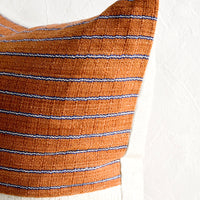 3: A throw pillow with top half in rust & indigo striped fabric and natural linen back.