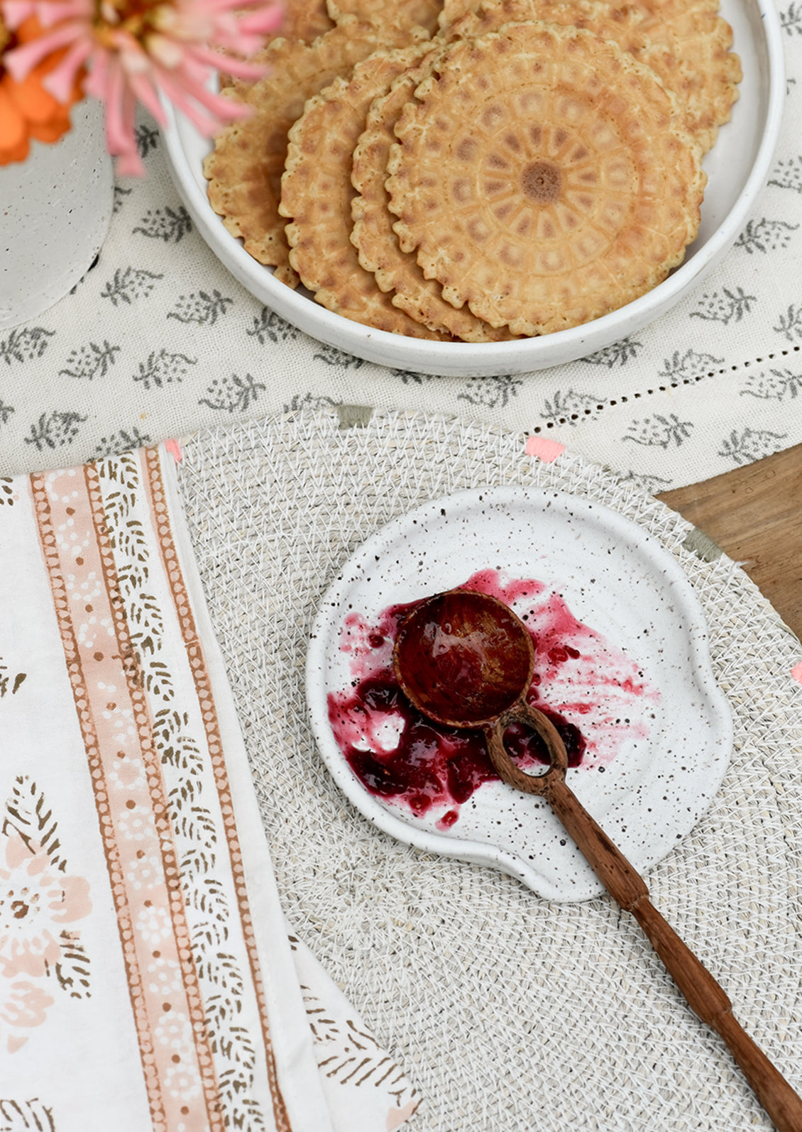 A spoon rest holding a wooden spoon covered in jam.