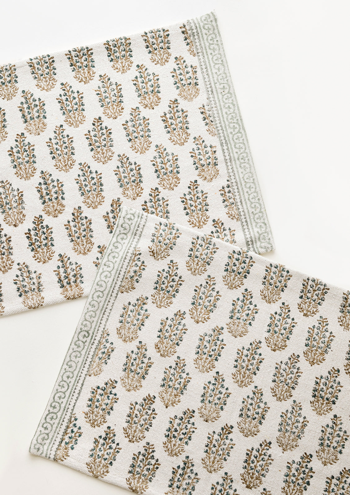 Two ivory rectangular cotton placemats with green floral pattern.