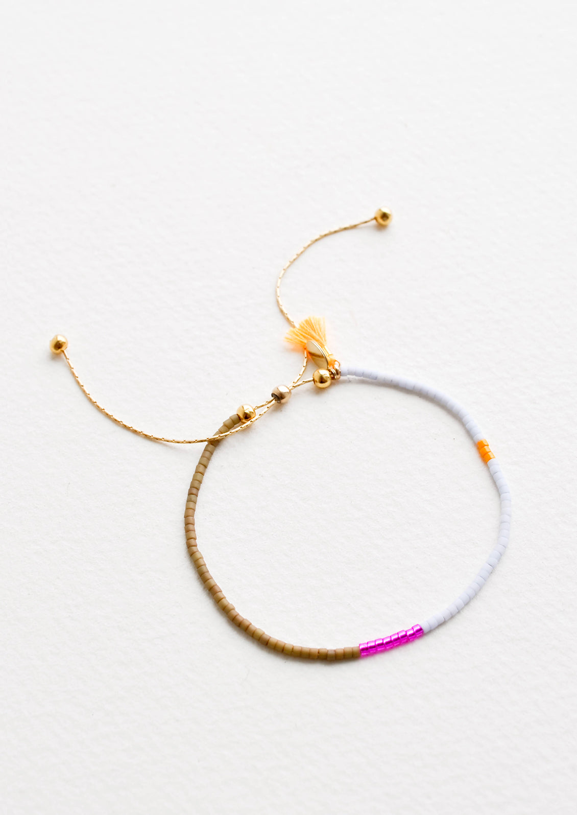 Delicate bracelet with sections of glass beads in khaki, metallic pink, light blue, and neon orange on a thin gold chain.