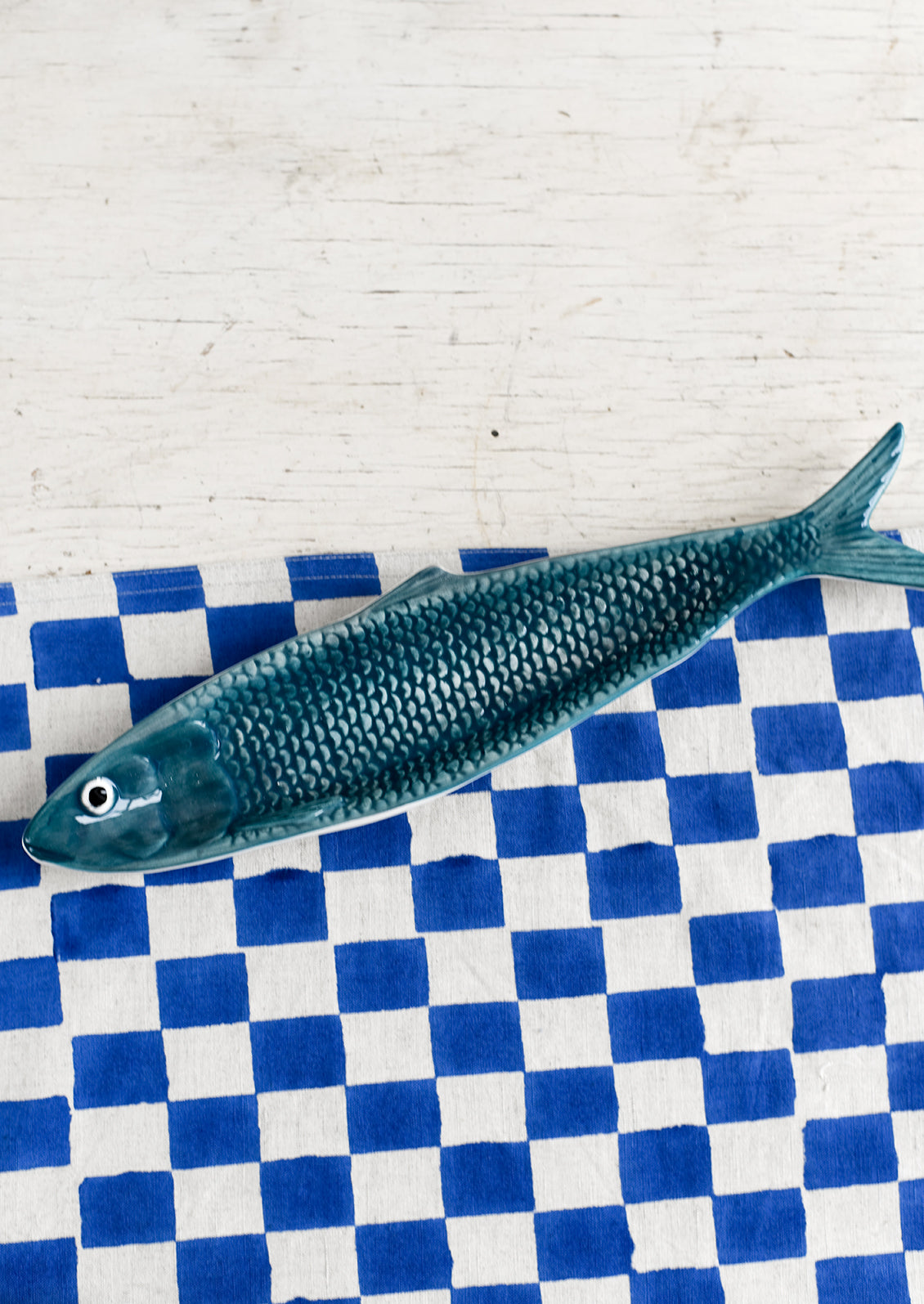 A ceramic tray in the shape of a sardine in teal.