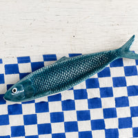 Teal: A ceramic tray in the shape of a sardine in teal.