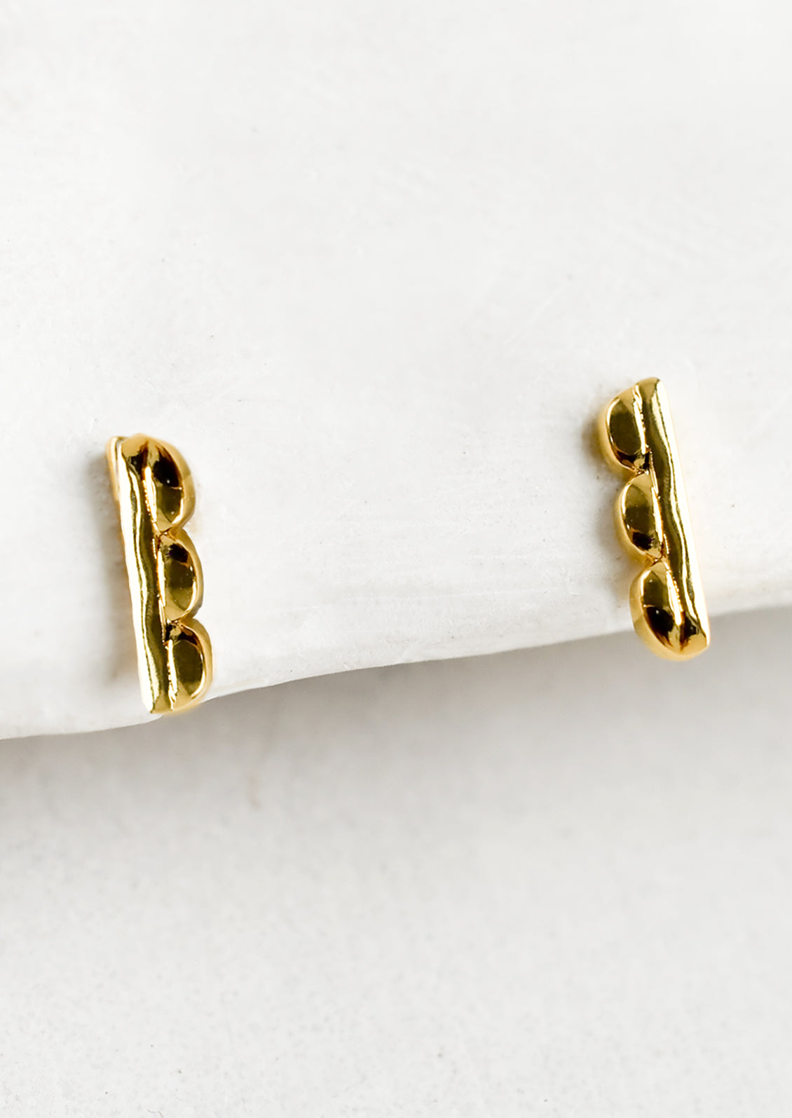 A pair of bar shaped stud earrings with scalloped edge.