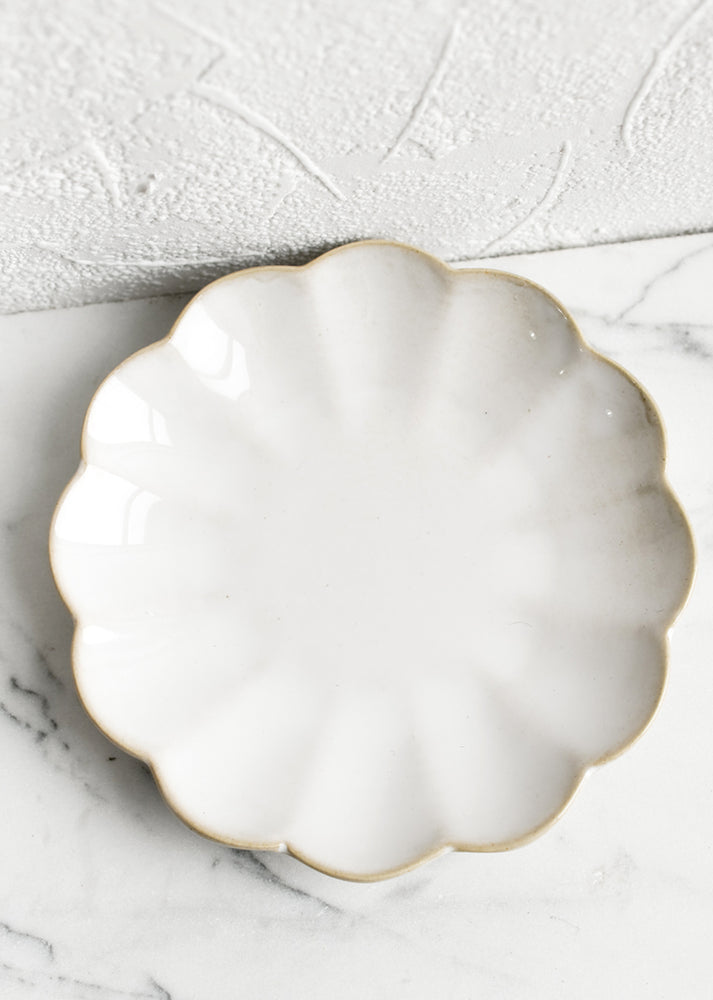 A small dessert plate in ceramic with scalloped shape.