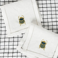 1: A pair of scarab embroidered cocktail napkins.