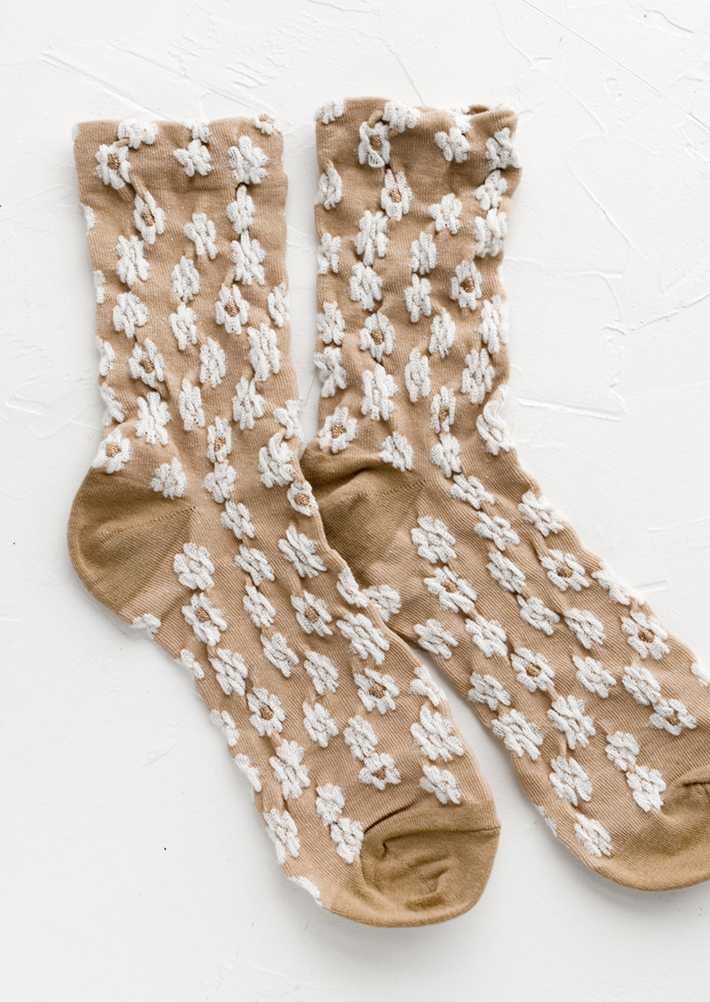 Tan: A pair of non-sheer yellow socks in tan with allover white daisy pattern.