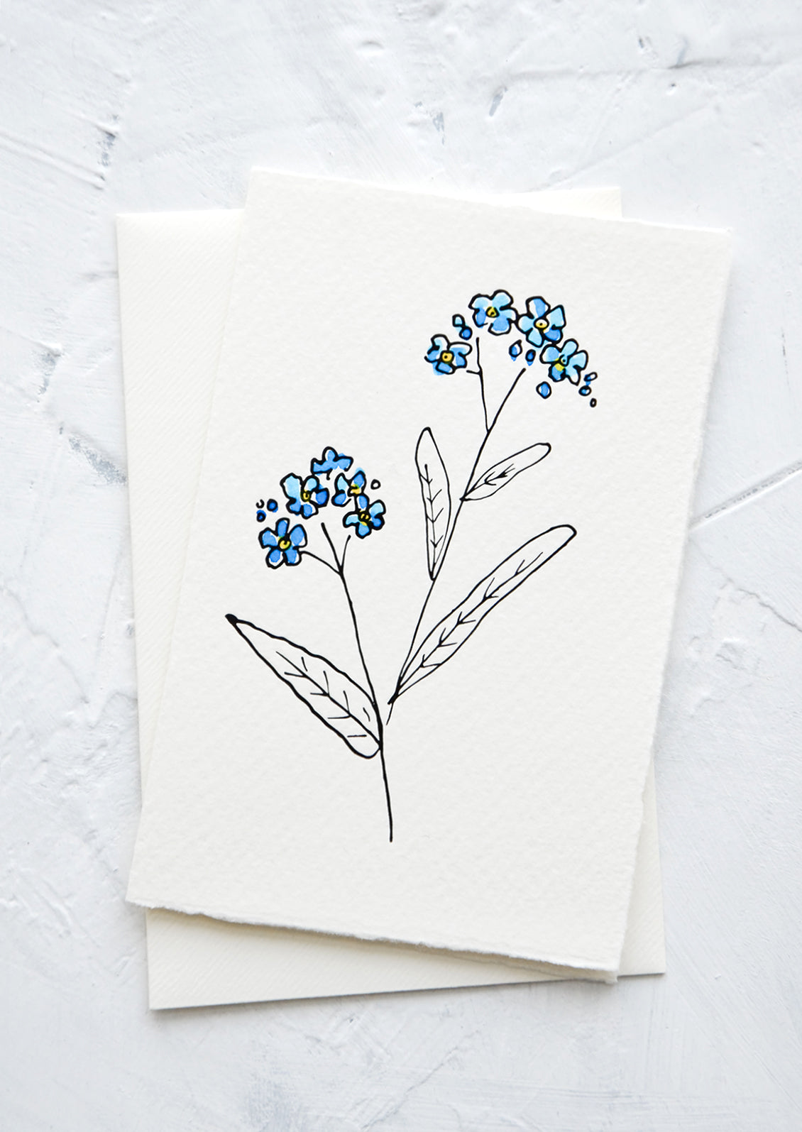 A letterpress printed greeting card made from hand-torn paper with hand-painted flower on front.