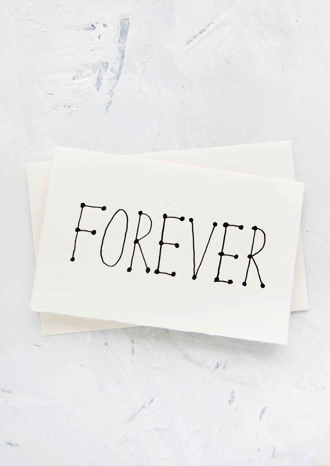 A letterpress printed greeting card made from handmade paper with "FOREVER" printed in black letters