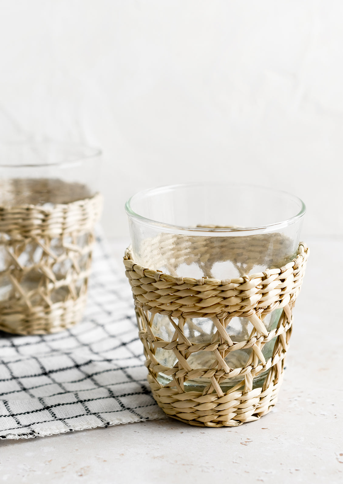 Small glass cups wrapped in decorative seagrass cage.