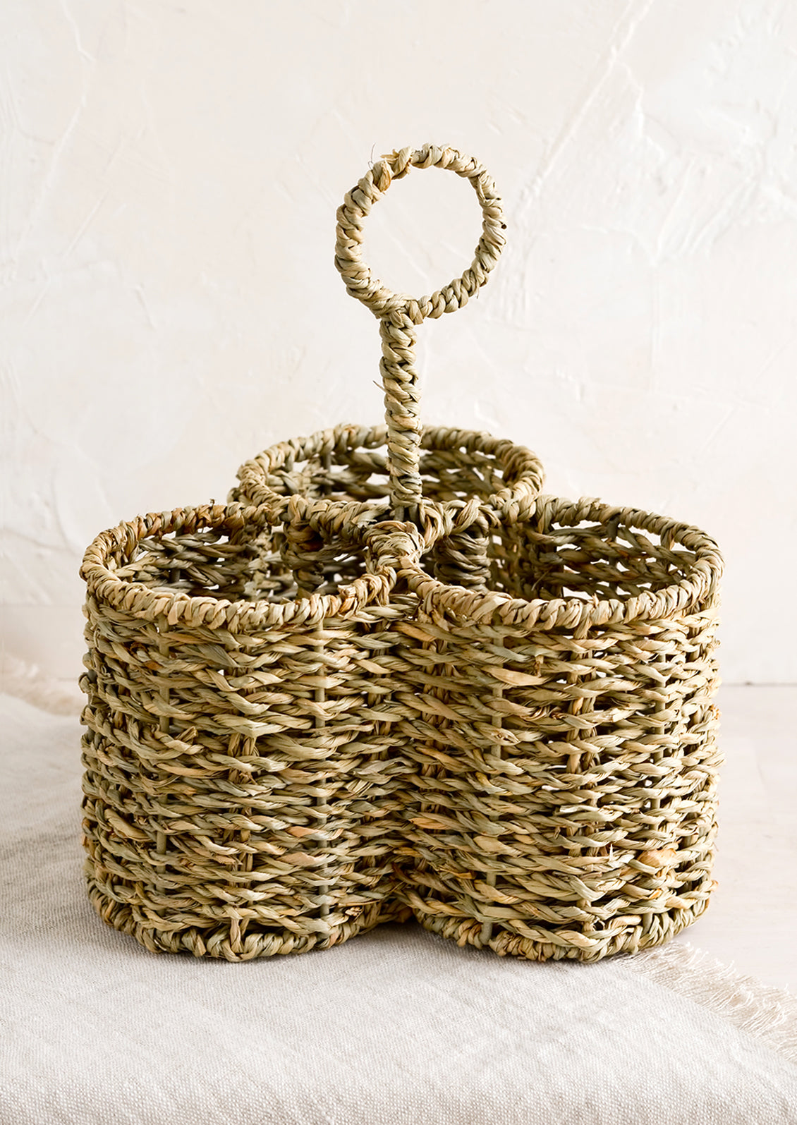 A utensil caddy with three divided sections, made from seagrass.