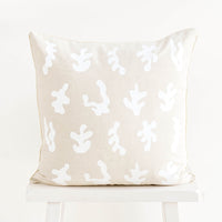 1: Square throw pillow in natural linen color with white, screen printed seaweed shapes 