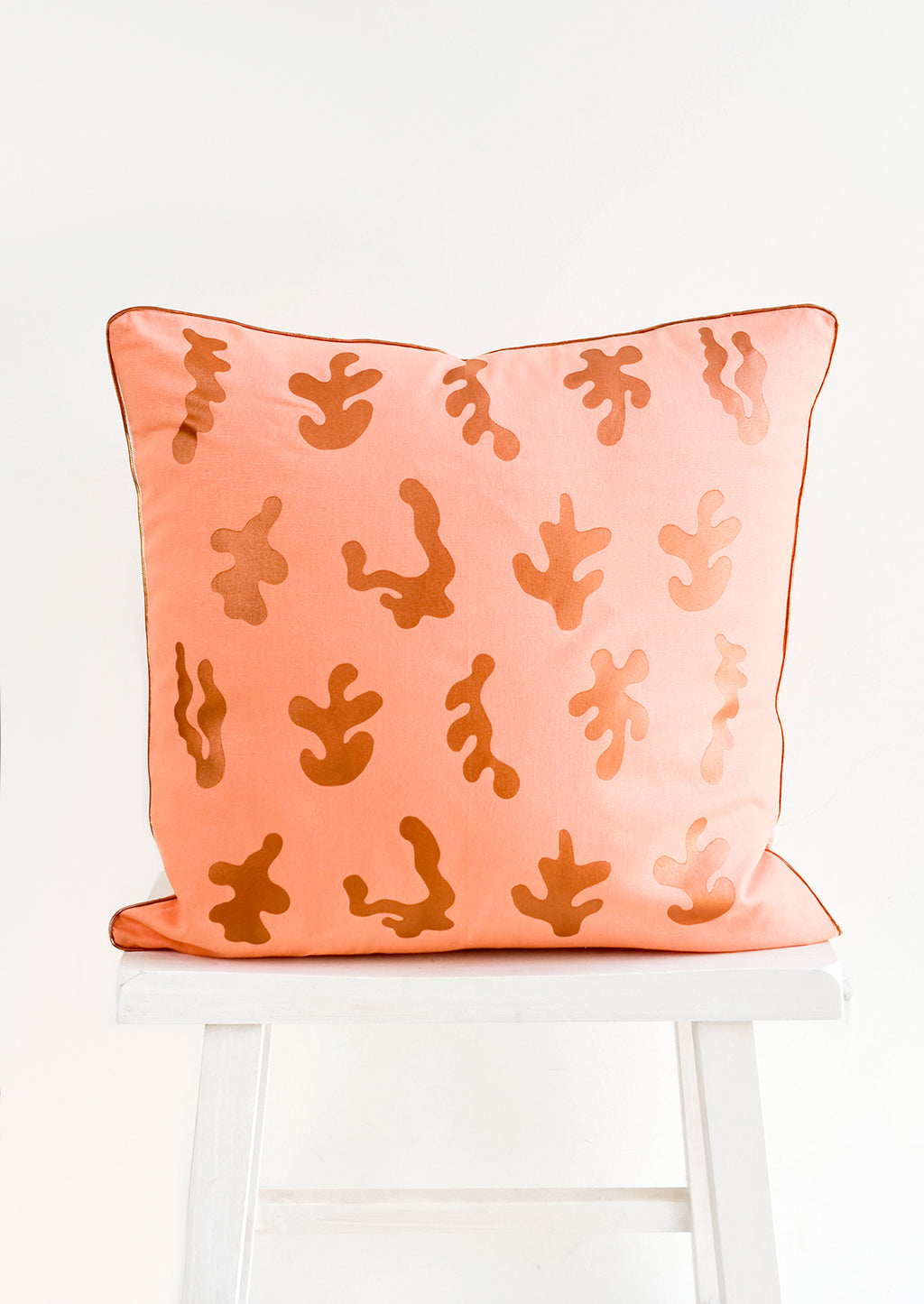 3: Square throw pillow in peach color with copper, screen printed seaweed shapes and copper trim