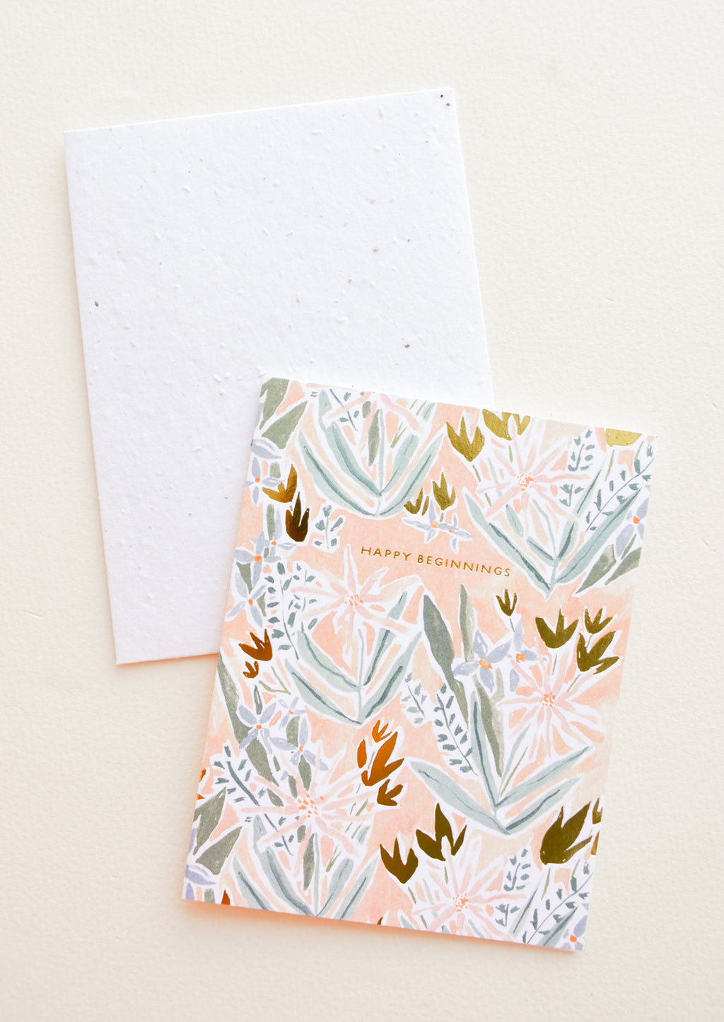 1: Greeting card in peach color with floral print and "Happy Beginnings" text