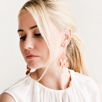 4: Model shot showing woman wearing earrings and a white top.