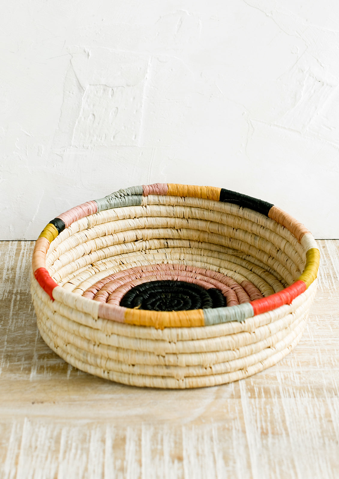 A round, shallow basket in colorful design.